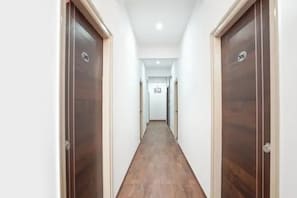 Um corredor com portas de madeira e chão de azulejos.