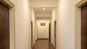 A hallway with wooden flooring, white walls, and doors on both sides.