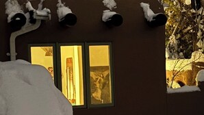 Ein Haus mit Schornstein, zwei erleuchteten Fenstern und Schnee auf dem Dach und dem Boden.
