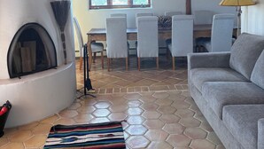 Ein Wohnzimmer mit Kamin, einer Couch, einem gemusterten Teppich und einem Essbereich mit Stühlen und Tisch.