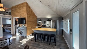 Une cuisine moderne avec un mur d’accent en bois, des appareils en acier inoxydable et un coin bar avec des tabourets.