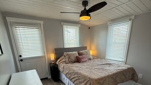 Une chambre à coucher avec un lit, un bureau et un ventilateur de plafond.