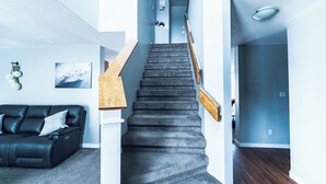 Un escalier avec des rampes en bois, un canapé en cuir noir et un tableau accroché au mur.