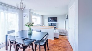 Un salon moderne avec un coin repas, un plancher en bois et une grande fenêtre.