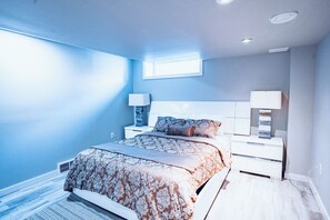 A bedroom with a bed, nightstands, and a window. - Spacious & cozy family/group-sized home with backyard, deck & Gazebo! (Winnipeg)