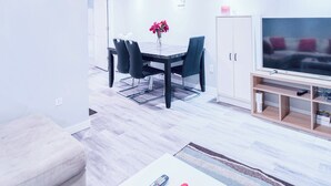 Un salon moderne comprenant un coin repas, un téléviseur et un meuble.