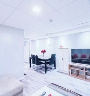 Un salon moderne comprenant un coin repas, un téléviseur et un meuble.