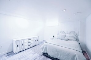 A bedroom with a bed, a dresser, a nightstand, and a window. - Spacious & cozy family/group-sized home with backyard, deck & Gazebo! (Winnipeg)