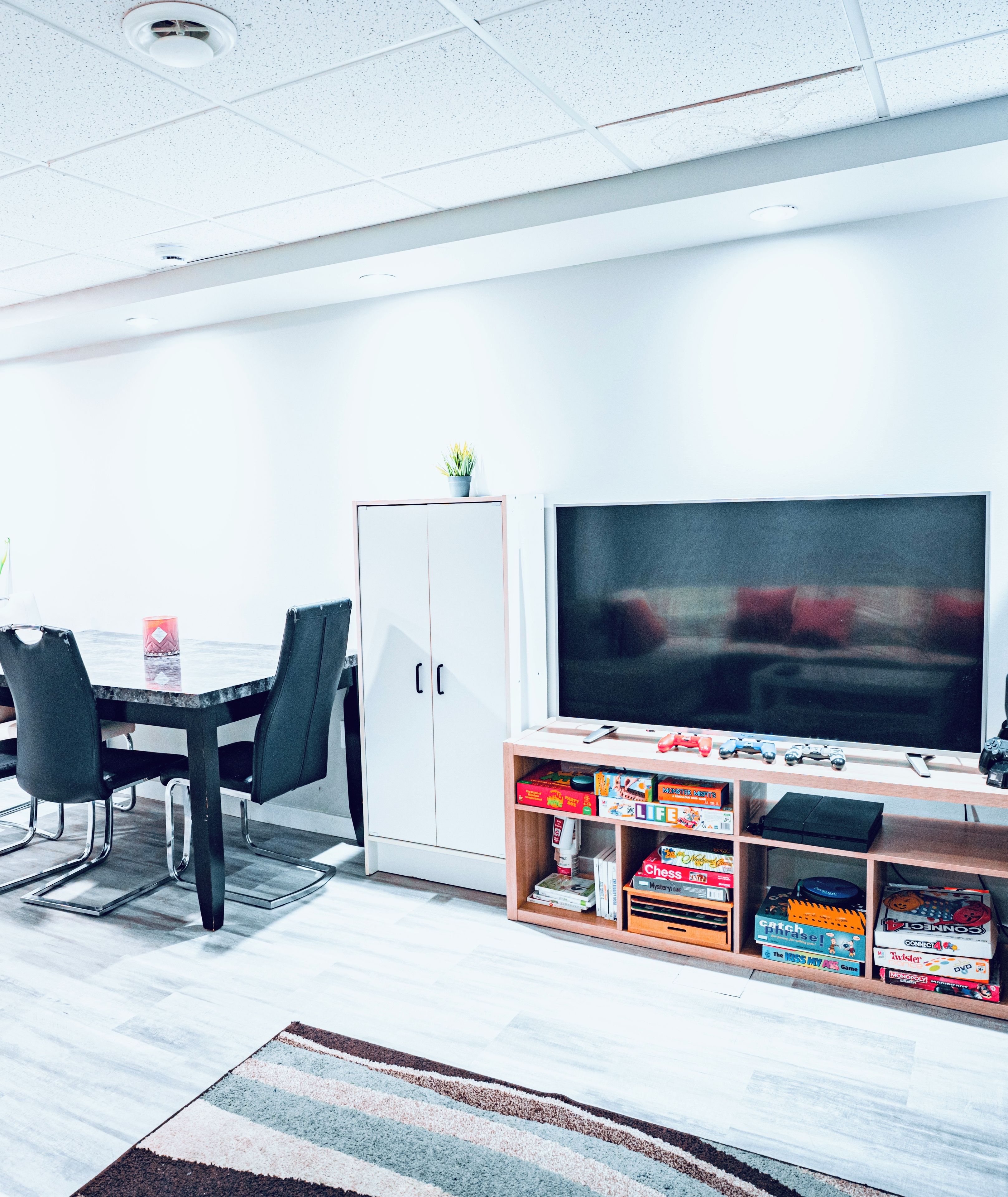 A modern room with a dining table, chairs, a cabinet, and a television.