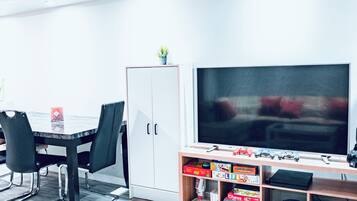 A modern room with a dining table, chairs, a cabinet, and a television.