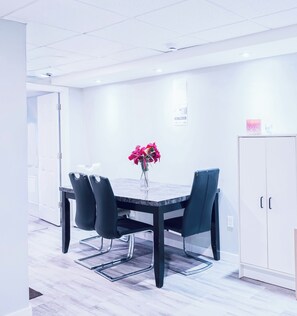 A modern dining area with a table, chairs, and a vase of flowers. - Spacious & cozy family/group-sized home with backyard, deck & Gazebo! (Winnipeg)