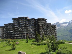 A multi-story building with balconies, surrounded by a grassy landscape and mountains in the background. - 200m from ski slopes, 5th floor, balcony, tv, 21m², Tignes (Tignes)