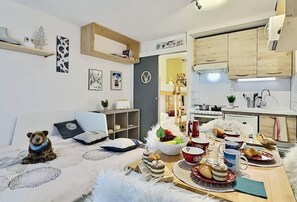 A cozy living room with a dining table set for a meal, a dog, and a kitchen area with wooden cabinets. - 200m from ski slopes, 5th floor, balcony, tv, 21m², Tignes (Tignes)
