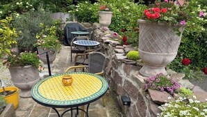 Un patio con muros de piedra, mobiliario exterior y plantas en macetas.