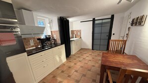 Una cocina compacta con armarios blancos, una encimera negra y suelo de baldosas.
