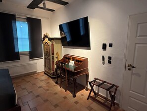 A room with a piano, a television, a door, and a window with blinds.