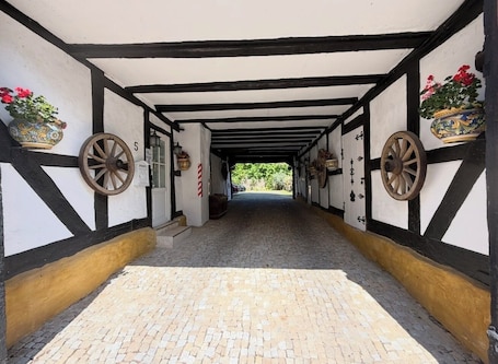 A corridor with a cobblestone floor, black and white walls, and decorative wheels.. Grebenstein with castle & towers near Sleeping Beauty's Sababurg & Rapunzel's Trendelburg