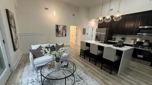 A modern kitchen with dark cabinets, a central island, and pendant lighting. - Sweet Atlanta Escape (Atlanta)