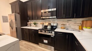 A modern kitchen with dark cabinets, stainless steel appliances, and a white countertop. - Sweet Atlanta Escape (Atlanta)