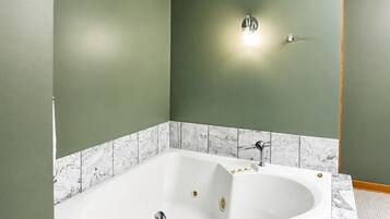 Une salle de bain avec une baignoire sur pieds, un luminaire fixé au mur et un système de ventilation.