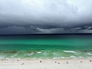 A beach with clear turquoise water, a sandy shore, and a cloudy sky. - Tropic Winds 1805 - Newly Remodeled Beachfront Condo + Free Beach Service (Panama City Beach)