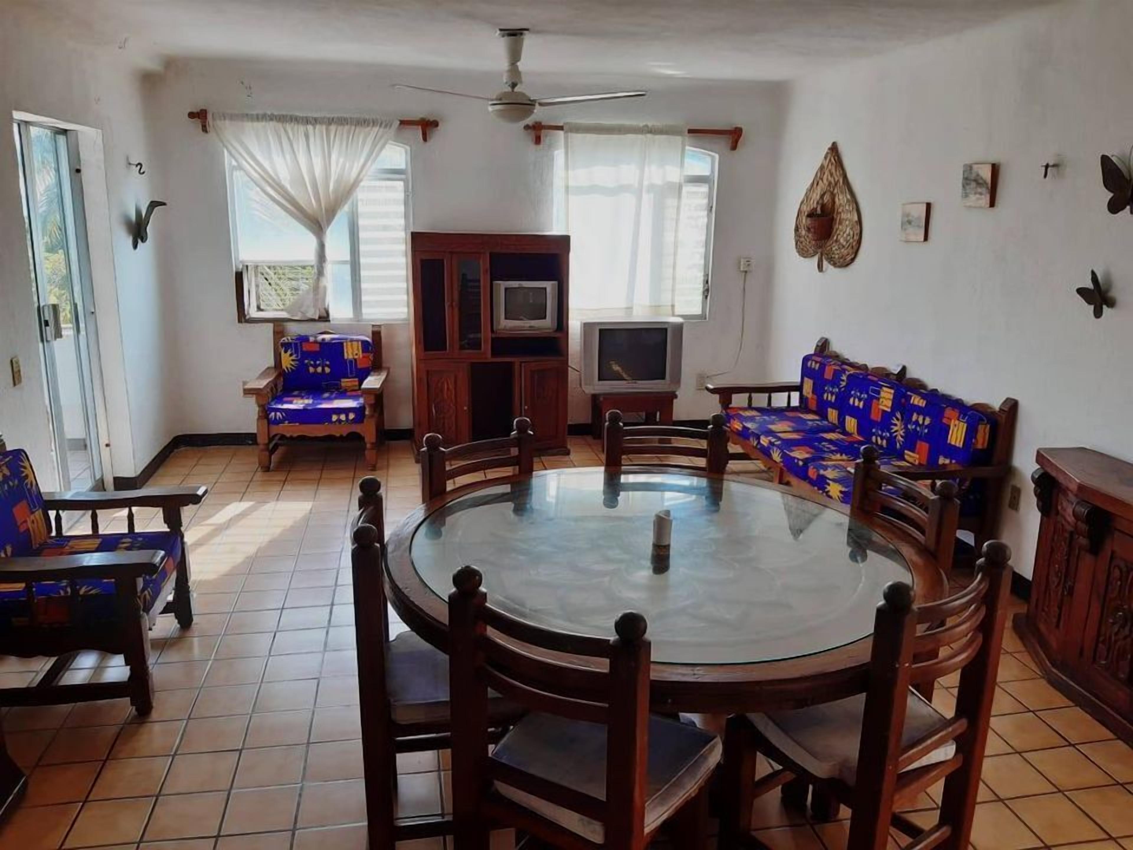 Un comedor con una mesa redonda, sillas de madera, un televisor y un sofá.