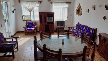 Un comedor con una mesa redonda, sillas de madera, un televisor y un sofá.