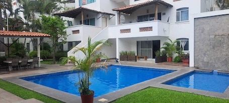A two-story building with a swimming pool, outdoor seating, and potted plants.. Hotel Brisasol