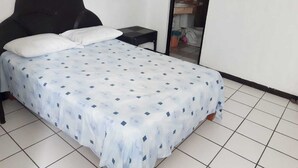 A bedroom with a bed, two pillows, a nightstand, and a mirror. - Hotel Brisasol (Manzanillo)