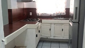 A kitchen with a gas stove, white cabinets, and a refrigerator. - Hotel Brisasol (Manzanillo)