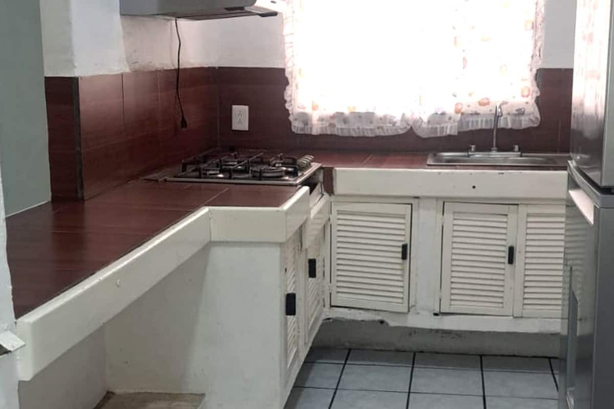 A kitchen with a gas stove, white cabinets, and a refrigerator.