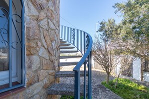 Eine Wendeltreppe mit Steinstufen und Metallgeländern, die zu einer Tür mit Fenster führt.