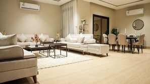 A modern living room with a sofa, coffee table, and dining area. - 5 mins to the sea ~1BR luxury apartment ~Pool ~ Fast Wi-Fi (Al Khobar)