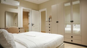 A hotel room with a bed, a desk, a chair, a wardrobe, and a mirror. - 5 mins to the sea ~1BR luxury apartment ~Pool ~ Fast Wi-Fi (Al Khobar)