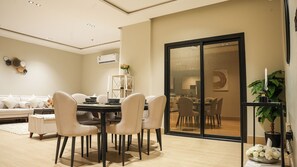 A dining area with a table, chairs, and a sofa in a modern interior. - 5 mins to the sea ~1BR luxury apartment ~Pool ~ Fast Wi-Fi (Al Khobar)