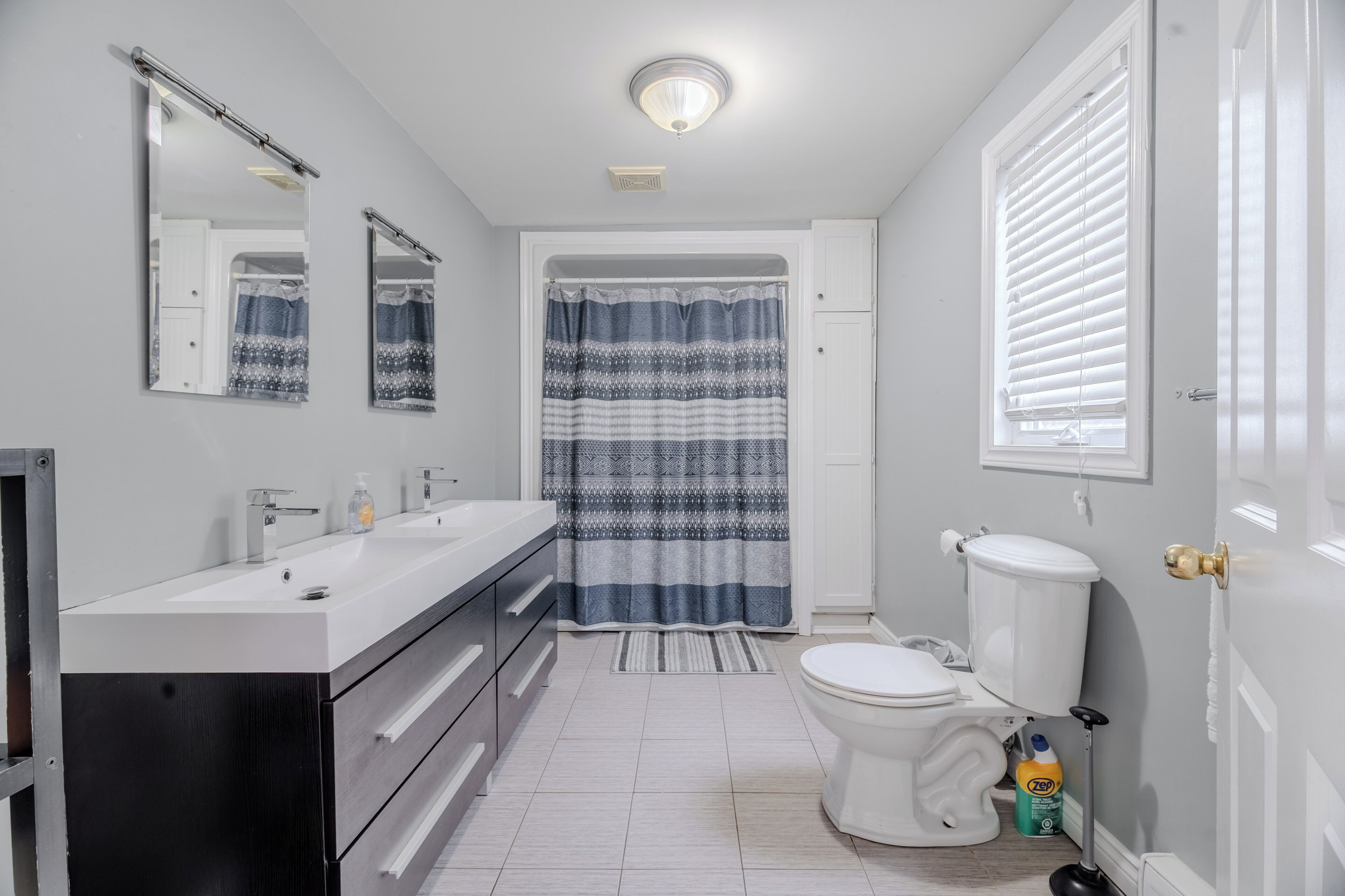 Een badkamer met een wit wastafel, spiegel, toilet en douchegordijn.