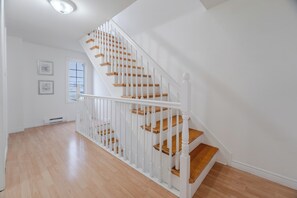 Eine Treppe mit weißen Geländern und Holzstufen, die zu einer Zwischenebene führt.