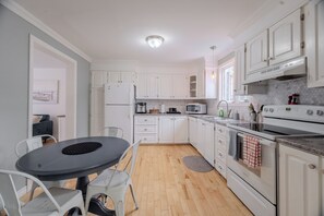 Una cocina moderna con armarios blancos, una mesa de comedor y un horno empotrado.