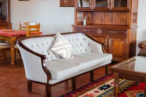 Une pièce avec un canapé capitonné, des meubles en bois et un tapis à motifs.