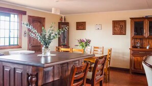 Un'ampia cucina con un'isola grande, sedie in legno, un tavolo da pranzo e un armadietto.