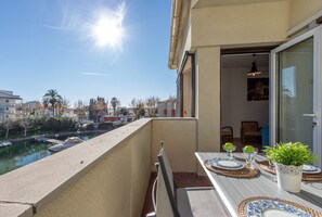 Een balkon met een eettafel, met uitzicht op een waterpartij en gebouwen.
