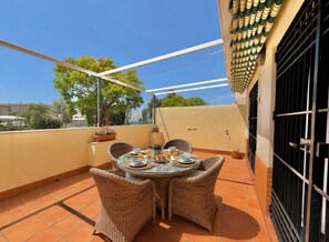 A rooftop terrace with a round table, wicker chairs, and a view of the city. - TERRASOL HOUSE CERRO DEL ÁGUILA (Torre del Mar)