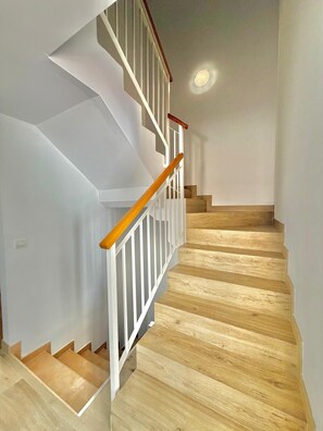 A staircase with wooden steps and white railings, leading to an upper floor.