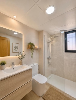 Ein modernes Badezimmer mit Glasdusche, Waschbecken in Weiß und Toilette.