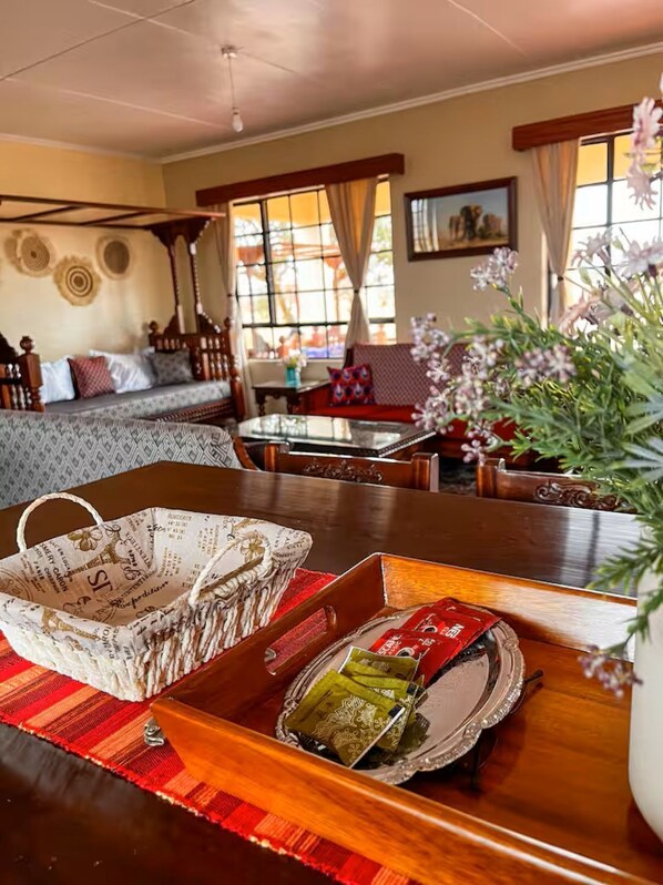 Une pièce avec une table à manger en bois, un canapé et une fenêtre avec des rideaux.