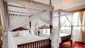 A double bed with a canopy, a wooden headboard, and a red carpet.