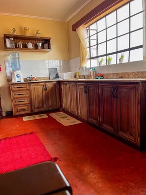 A kitchen with wooden cabinets, a water dispenser, and a window with potted plants.