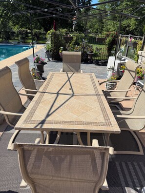 Une terrasse avec une table et des chaises, une piscine et des plantes en pot.