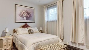 A neatly arranged bedroom with a bed, bedside tables, a wall-mounted artwork, and a window with curtains. - Niagara River Idyll
Luxurious Queen size bedroom with own bathroom (Stevenstille)