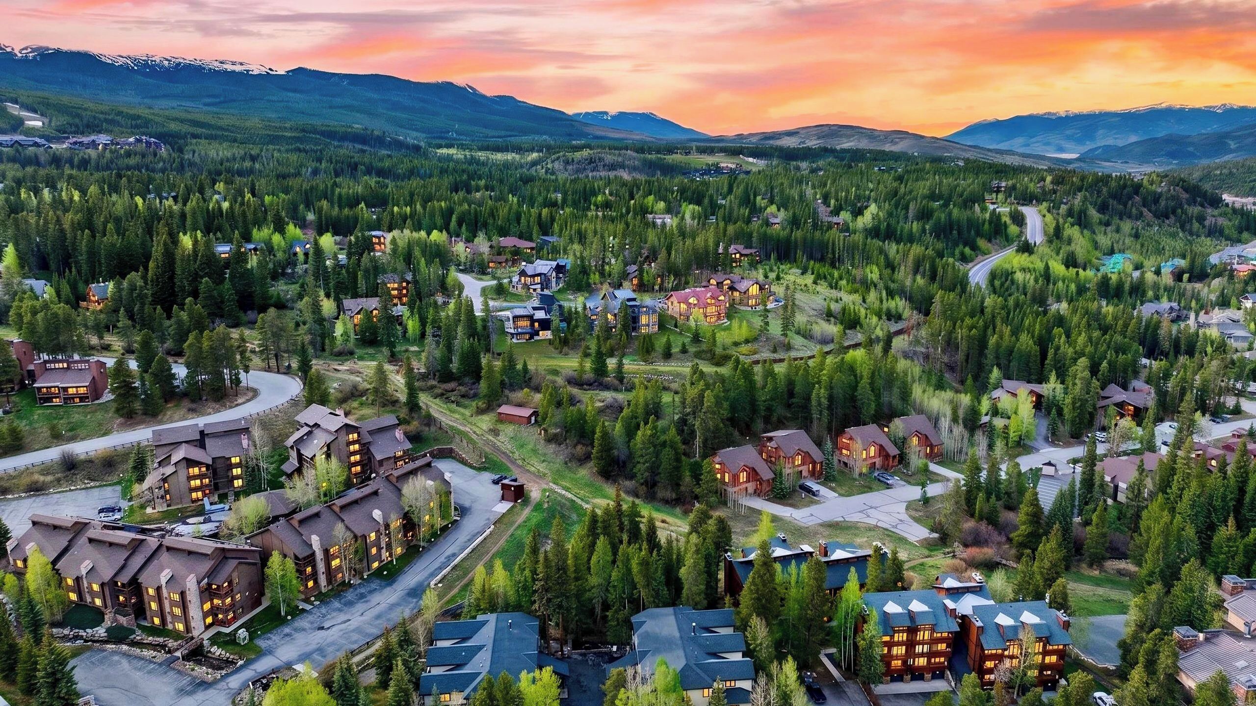 A residential area with multiple houses, roads, and a mountainous backdrop.